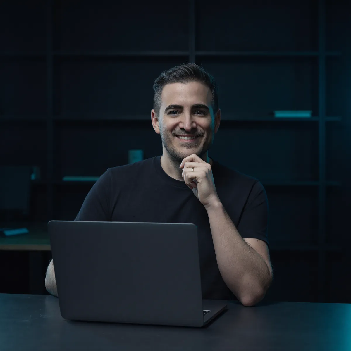 Javier Yranzo sonriendo frente a su laptop, con la mano en el mentón